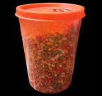 Desipan assorted candy-coated seeds in a bright orange plastic container. Mix of red, orange, yellow, and green seeds.