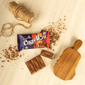 Desipan Cadbury Dairy Milk Crispy Chocolate Bar with crispy pieces and a wooden board.