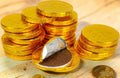 Desipan chocolate coins wrapped in gold foil, one coin unwrapped revealing milk chocolate inside.