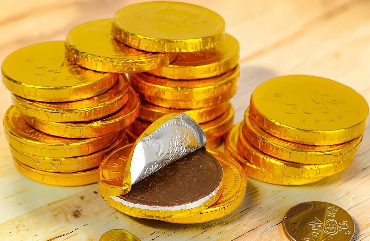 Desipan chocolate coins wrapped in gold foil, one coin unwrapped revealing milk chocolate inside.
