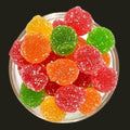 Desipan assorted fruit flavored gummy candies in red, orange, green, and yellow, coated in sugar.