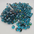 Desipan glass marbles in translucent blue with red, orange, and yellow swirls, perfect for games and crafts.