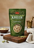 Desipan Kings Vermicelli Kheer Payasam Mix in a green pouch with cardamom pods on a wooden board.