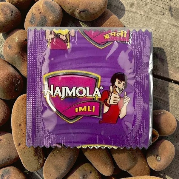Desipan Najmola Imli candy wrapper with a cartoon man giving thumbs up. Purple wrapper with yellow and pink accents.