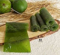 Desipan traditional raw mango fruit leather rolls with a chewy texture and vibrant emerald green color on a wood board