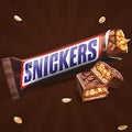 Desipan Snickers chocolate candy bar with peanuts, caramel, and nougat, partially unwrapped.