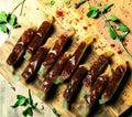 Desipan spicy sausage sticks individually wrapped in clear plastic, showcasing a rich, dark red color and textured filling.