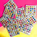 Desipan assorted star shaped candy tablets in pink, blue, yellow, orange, and white, packaged in blister packs.