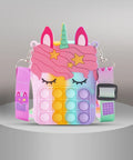 Desipan unicorn pop-it shoulder bag for kids, rainbow silicone with pink mane, stars, and green horn.